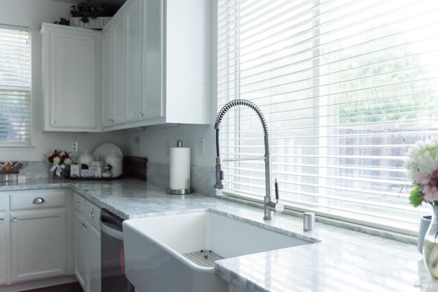 kitchen featuring a sink, light stone countertops, and white cabinetry