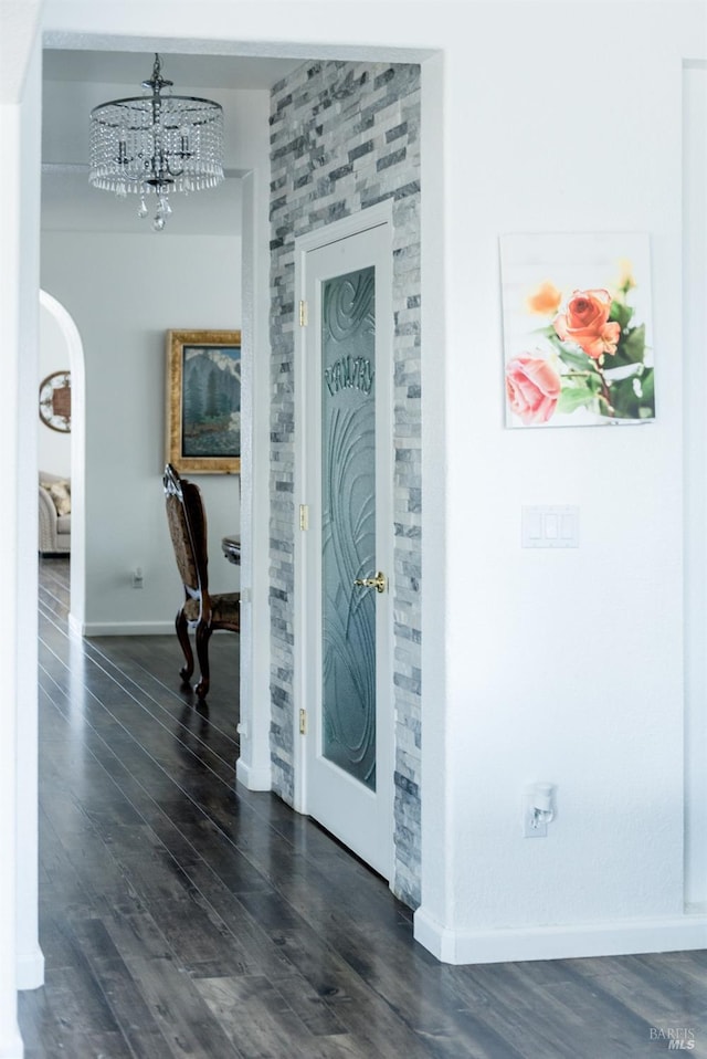 foyer featuring dark wood-style flooring, baseboards, a chandelier, and arched walkways