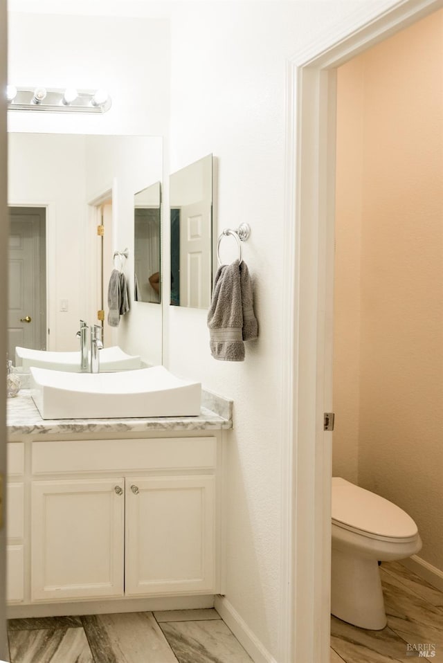 bathroom with vanity, toilet, and baseboards