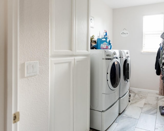 washroom featuring washer and clothes dryer, cabinet space, and baseboards