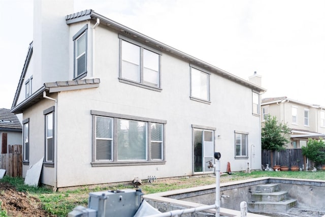 rear view of house with fence and stucco siding
