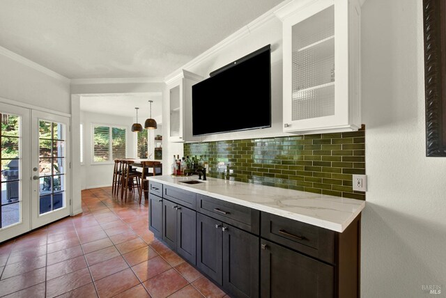 bar area featuring french doors, tasteful backsplash, a sink, dark tile patterned floors, and crown molding
