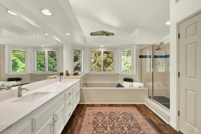 bathroom with plenty of natural light, wood finished floors, a garden tub, vaulted ceiling, and recessed lighting