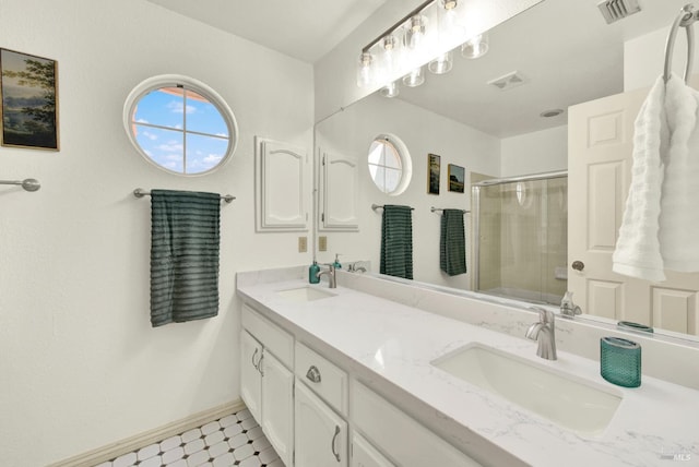 full bath featuring a shower stall, double vanity, and baseboards