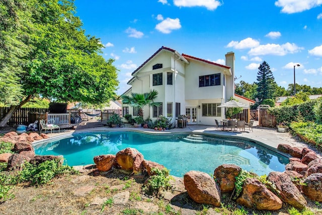 view of pool with french doors, a fenced backyard, a patio area, and a deck