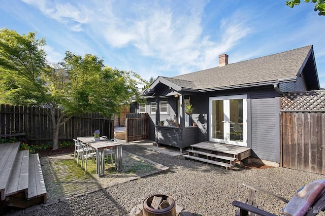rear view of house with a fenced backyard, a chimney, french doors, and a deck
