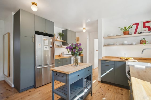 kitchen with open shelves, wooden counters, freestanding refrigerator, and light wood-style flooring