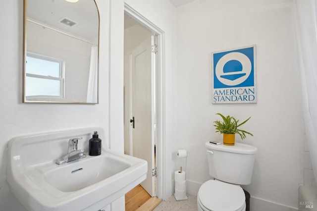 bathroom with a sink, toilet, and speckled floor
