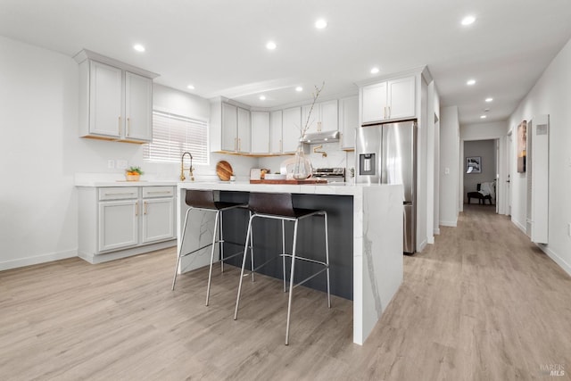 513 Verde Ave, Richmond, CA 94801 - kitchen featuring appliances with stainless steel finishes, a kitchen island, light wood-style floors, light countertops, and under cabinet range hood