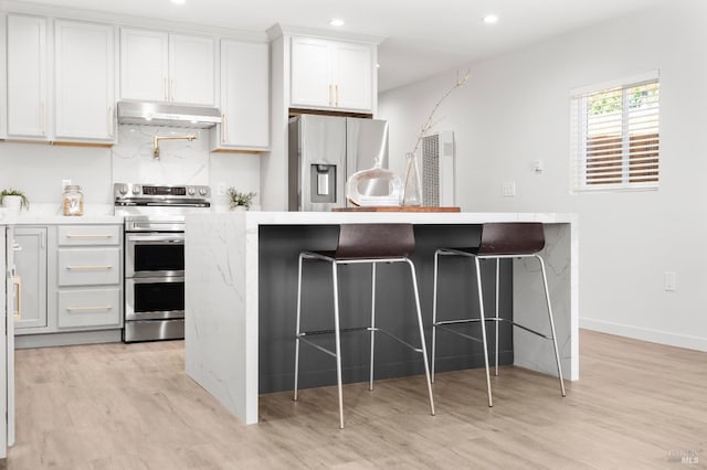 513 Verde Ave, Richmond, CA 94801 - kitchen with stainless steel appliances, under cabinet range hood, light wood-type flooring, a breakfast bar area, and recessed lighting