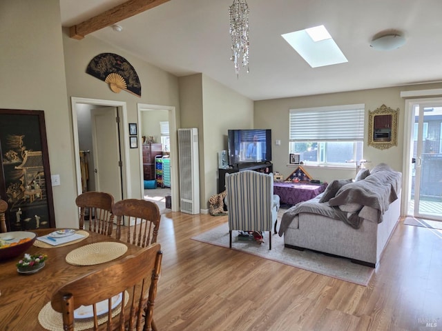 living room featuring a heating unit, a skylight, plenty of natural light, and light wood-type flooring
