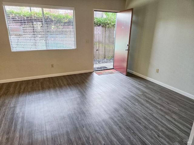 spare room with dark wood-style flooring and baseboards