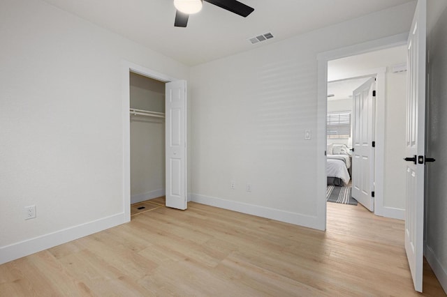 unfurnished bedroom with light wood finished floors, baseboards, ceiling fan, and a closet