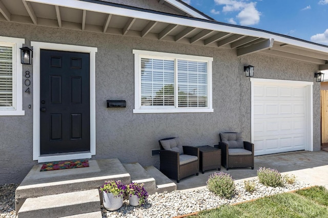 entrance to property featuring stucco siding, a garage, and driveway