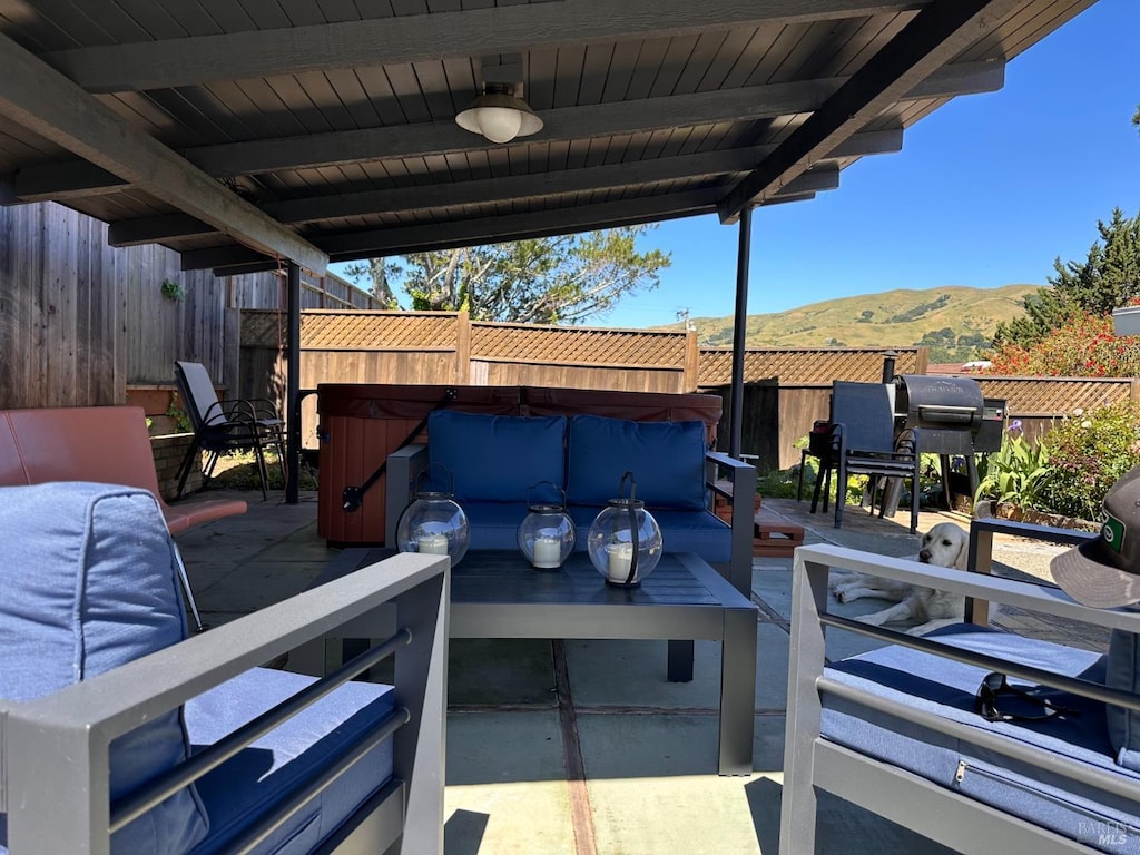 view of patio with an outdoor living space, a fenced backyard, a mountain view, and area for grilling