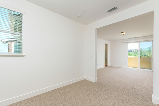 unfurnished room featuring light colored carpet, baseboards, and a smoke detector