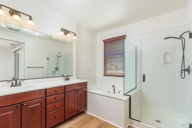 full bathroom featuring a stall shower, double vanity, a garden tub, and wood finished floors