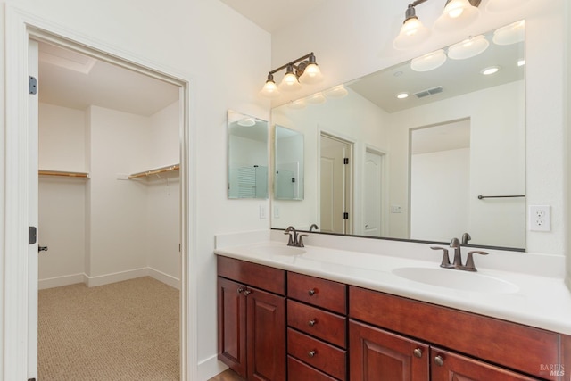 bathroom with double vanity, a spacious closet, and baseboards