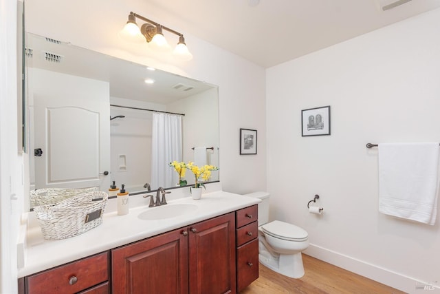 bathroom featuring wood finished floors, baseboards, vanity, toilet, and curtained shower
