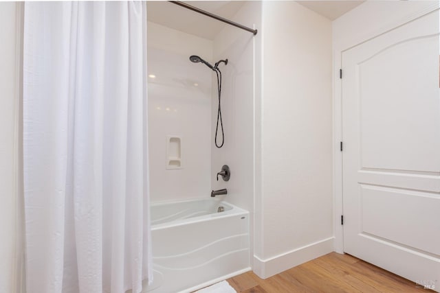 full bathroom with wood finished floors, baseboards, and shower / bathtub combination with curtain