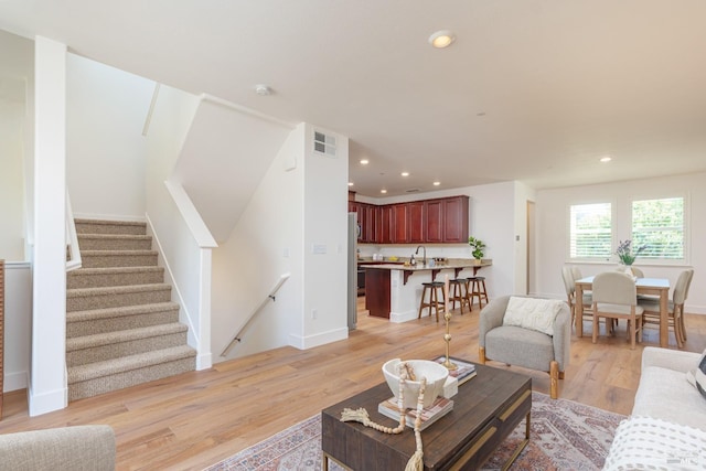 living room with recessed lighting, light wood-style floors, stairs, and baseboards
