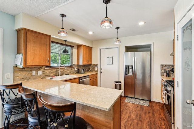 134 Lassen Cir, Vacaville, CA 95687 - kitchen featuring stainless steel appliances, brown cabinetry, a peninsula, a sink, and dark wood finished floors
