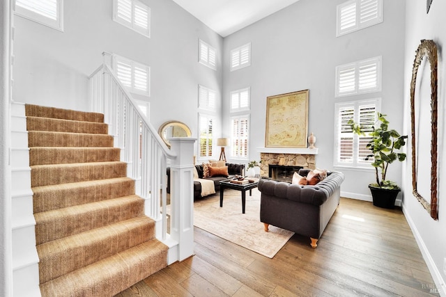653 Robinson Way, Benicia, CA 94510 - living room with light wood finished floors, a towering ceiling, stairs, baseboards, and a stone fireplace