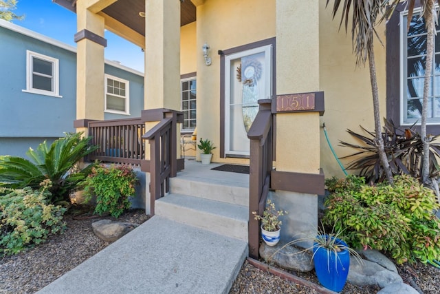 view of exterior entry featuring a porch and stucco siding
