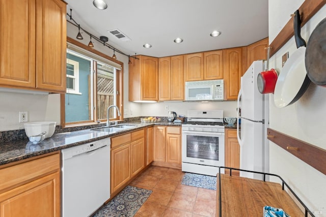 kitchen featuring white appliances, a sink, dark stone countertops, recessed lighting, and light tile patterned floors