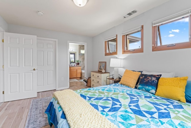 bedroom featuring light wood-type flooring, ensuite bathroom, and baseboards
