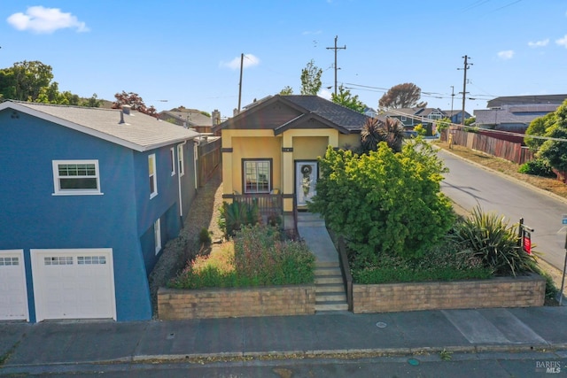 view of front facade with stucco siding, a garage, and fence
