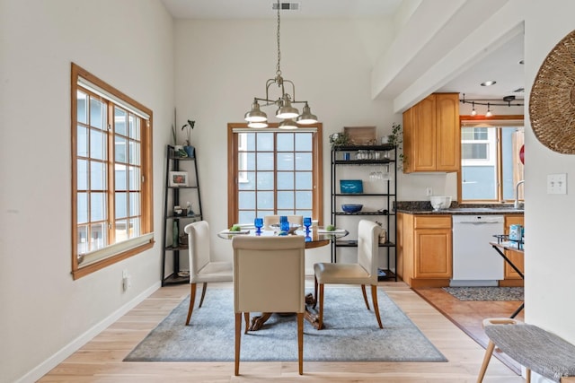 dining area with light wood-style floors, a chandelier, a towering ceiling, and baseboards
