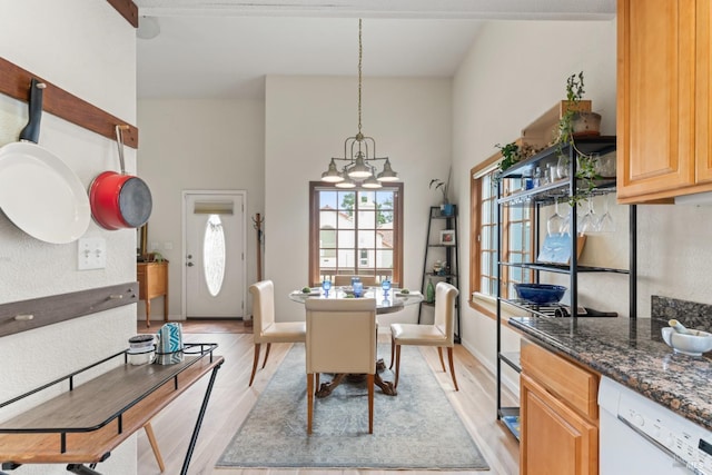 dining space with light wood finished floors, a chandelier, and baseboards
