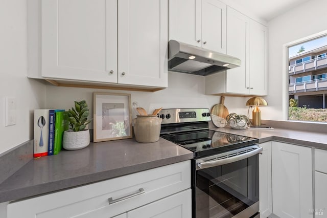kitchen featuring electric stove, under cabinet range hood, white cabinets, and dark stone counters