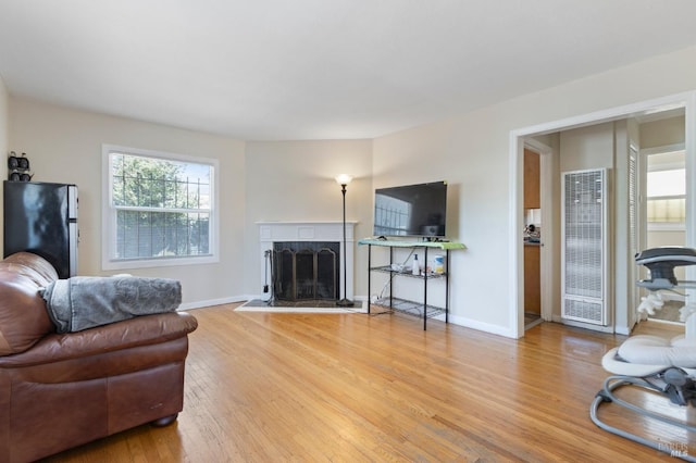 1741 84th Ave, Oakland, CA 94621 - living area featuring a heating unit, light wood-type flooring, a fireplace with raised hearth, and baseboards
