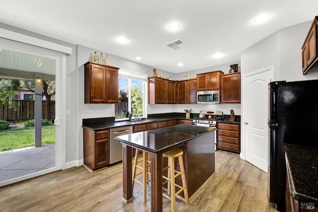 212 Via Del Sol, Vacaville, CA 95687 - kitchen with stainless steel appliances, a sink, light wood-type flooring, a breakfast bar area, and a center island