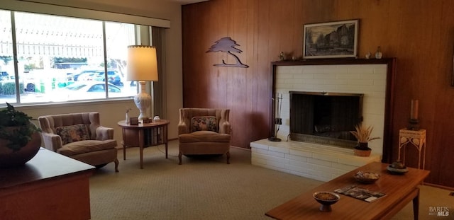 sitting room featuring carpet flooring, wood walls, and a brick fireplace