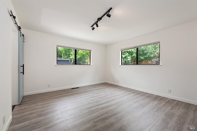 8940 Irving St, Graton, CA 95444 - unfurnished room featuring wood finished floors, healthy amount of natural light, a barn door, and baseboards