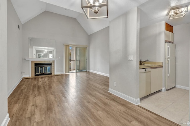 3183 Wayside Plz Unit 319, Walnut Creek, CA 94597 - unfurnished living room featuring a chandelier, light wood-style flooring, a tiled fireplace, high vaulted ceiling, and a sink