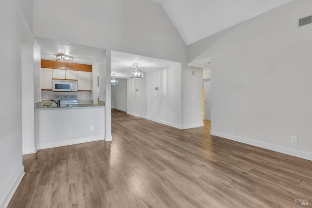 3183 Wayside Plz Unit 319, Walnut Creek, CA 94597 - unfurnished living room featuring wood finished floors, a chandelier, baseboards, and high vaulted ceiling