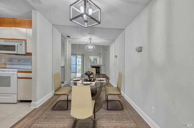 3183 Wayside Plz Unit 319, Walnut Creek, CA 94597 - dining room with light wood-style floors, a chandelier, baseboards, and a glass covered fireplace