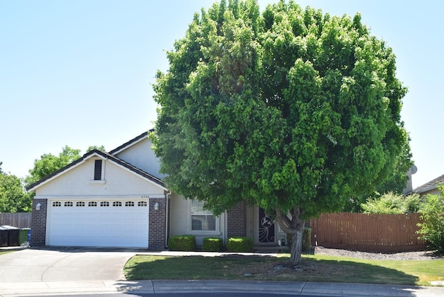 view of front of house featuring driveway, brick siding, an attached garage, and stucco siding