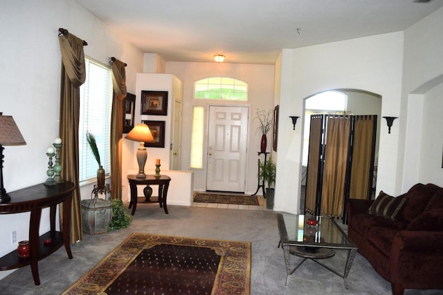 foyer entrance with carpet, arched walkways, and plenty of natural light
