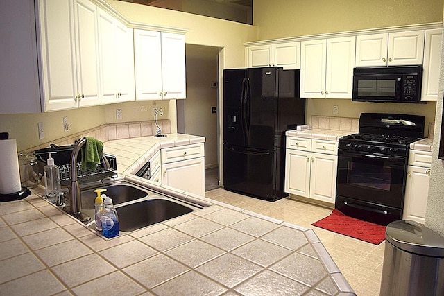 kitchen with black appliances, tile counters, a sink, and white cabinetry