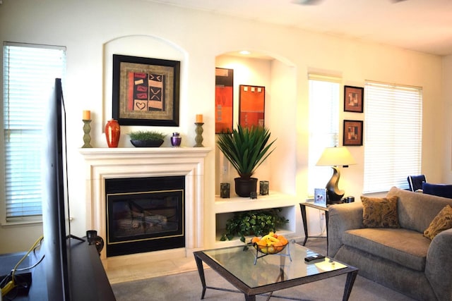 living area featuring a glass covered fireplace, arched walkways, and plenty of natural light