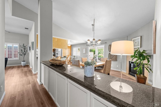 21 Autumn Creek Ct, Napa, CA 94559 - kitchen with wood finished floors, baseboards, dark stone counters, stainless steel refrigerator with ice dispenser, and lofted ceiling