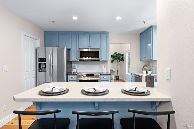 14 Ceriani Ct, Napa, CA 94558 - kitchen with appliances with stainless steel finishes, blue cabinets, a peninsula, a breakfast bar area, and recessed lighting