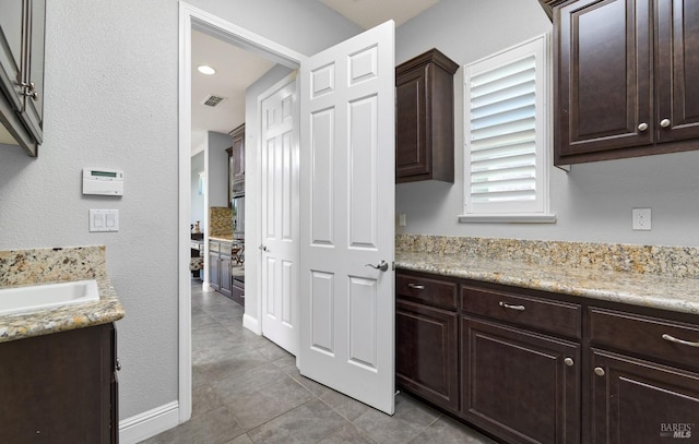 339 Desert Forest Ct, Rio Vista, CA 94571 - kitchen featuring dark brown cabinets, a sink, light tile patterned floors, oven, and light stone countertops