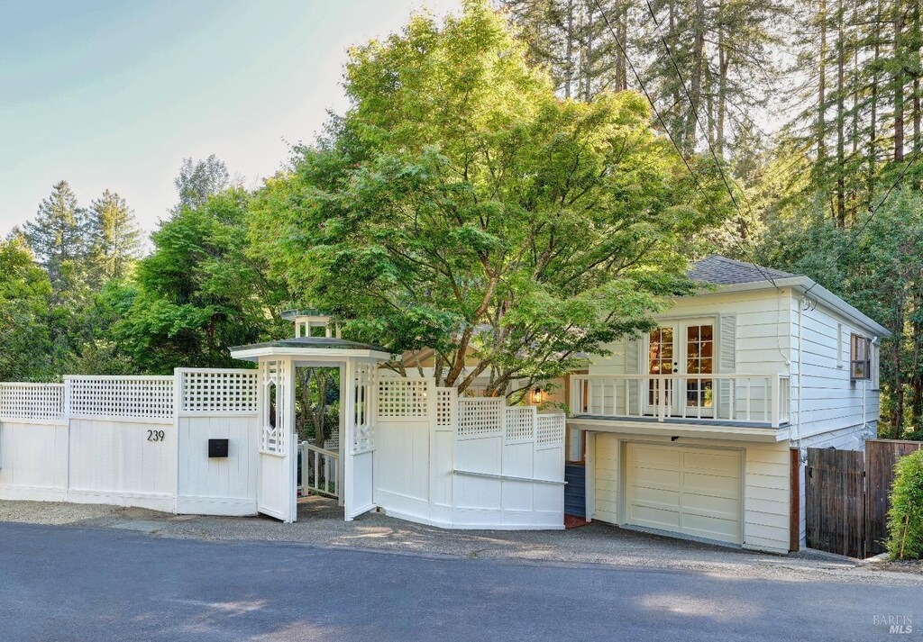 239 W Blithedale Ave, Mill Valley, CA 94941 - view of front of property with fence, a garage, view of wooded area, and asphalt driveway