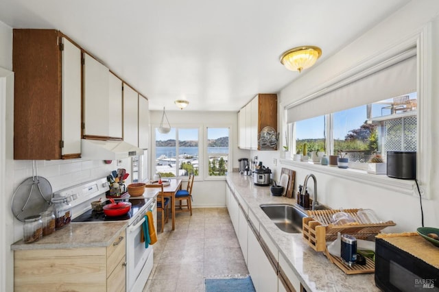 503 Easterby St, Sausalito, CA 94965 - kitchen featuring white electric range oven, a sink, under cabinet range hood, baseboards, and a water view